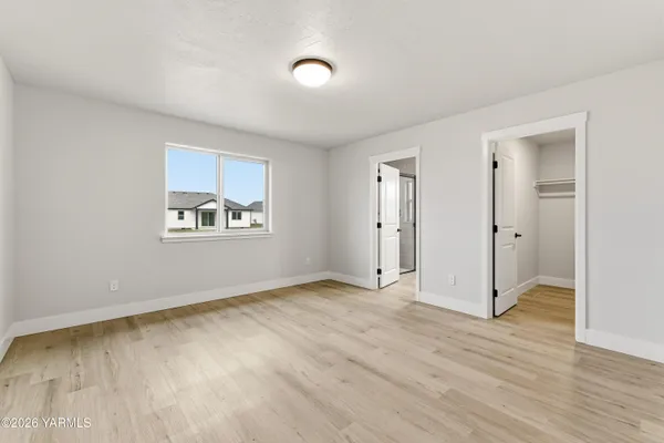 an empty room with wooden floor closet and windows