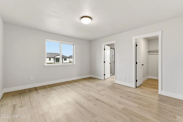 an empty room with wooden floor closet and windows