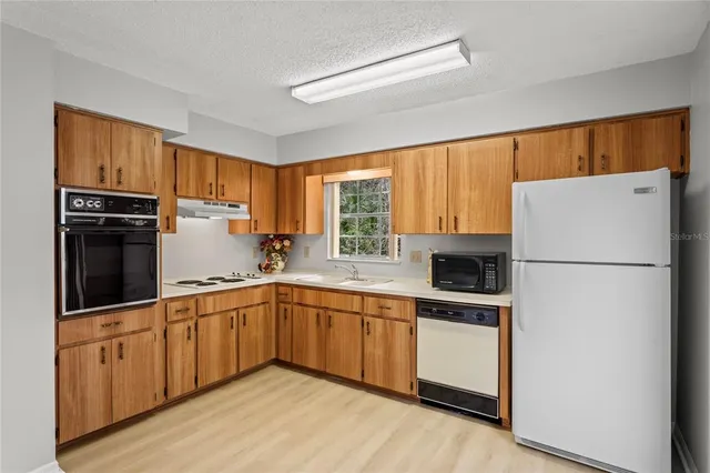 a kitchen with a sink a refrigerator and a stove top oven