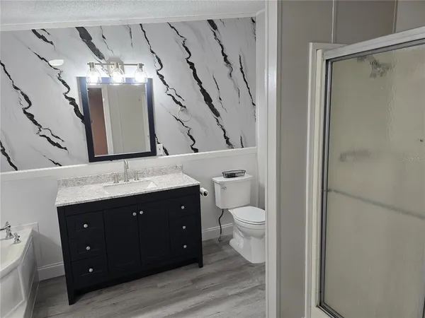 a spacious bathroom with a granite countertop sink toilet and shower