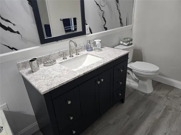 a bathroom with a granite countertop sink a toilet and mirror