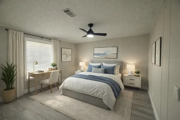 a bedroom with a large bed and a chandelier fan