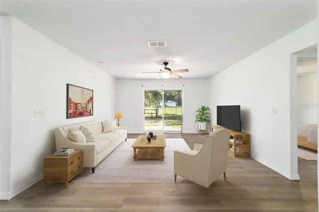 an empty room with wooden floor ceiling fan and window