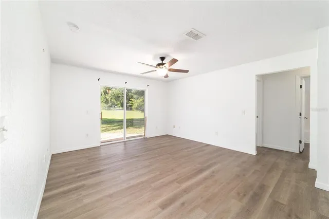 a view of an empty room with a window and wooden floor