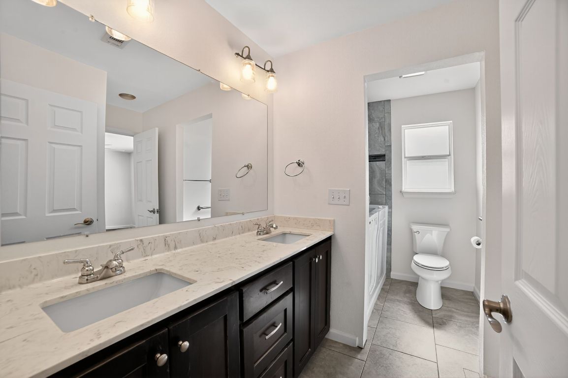 313 Starview Drive Georgetown, TX 78628 - Photo 29 of 38 a bathroom with a granite countertop sink a toilet and a mirror