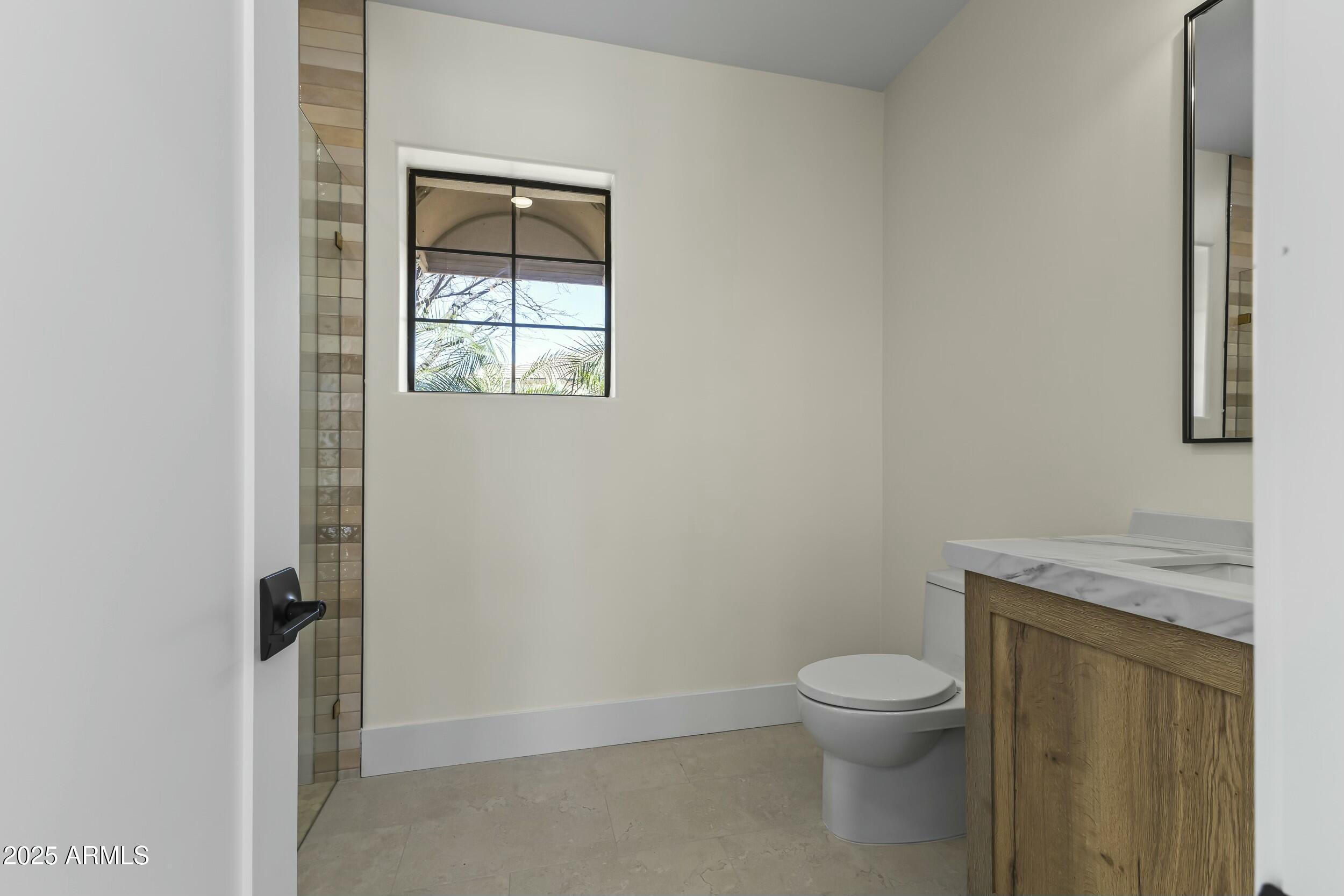 7705 East Doubletree Ranch Road, Unit 21 Scottsdale, AZ 85258 - Photo 29 of 45 a bathroom with a granite countertop toilet a sink and a window