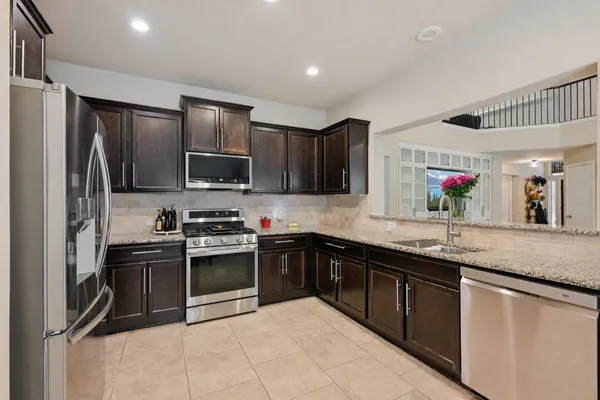 a kitchen with stainless steel appliances granite countertop a sink dishwasher stove top oven and refrigerator