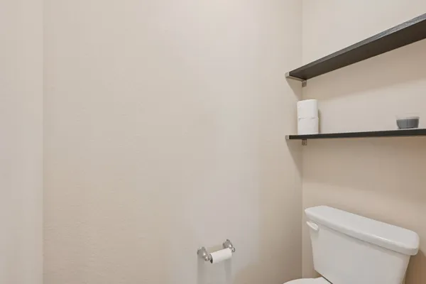 a white toilet sitting next to a white wall