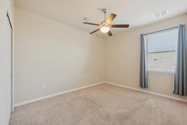 an empty room with a window and a ceiling fan