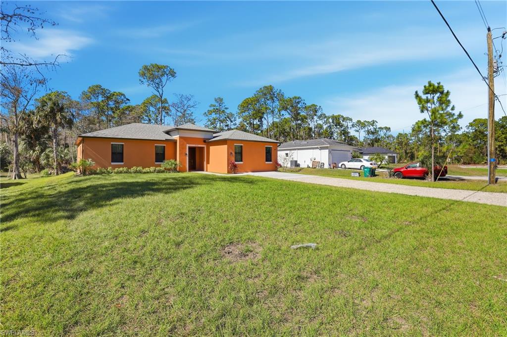 2167 Della Drive Naples, FL 34117 - Photo 3 of 38 View of front of home with a front yard, stucco siding, and driveway