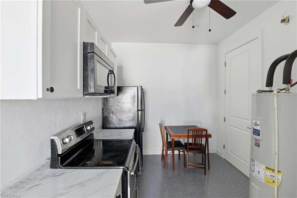 2167 Della Drive Naples, FL 34117 - Photo 29 of 38 Kitchen with stainless steel range with electric cooktop, black microwave, water heater, white cabinets, and a ceiling fan