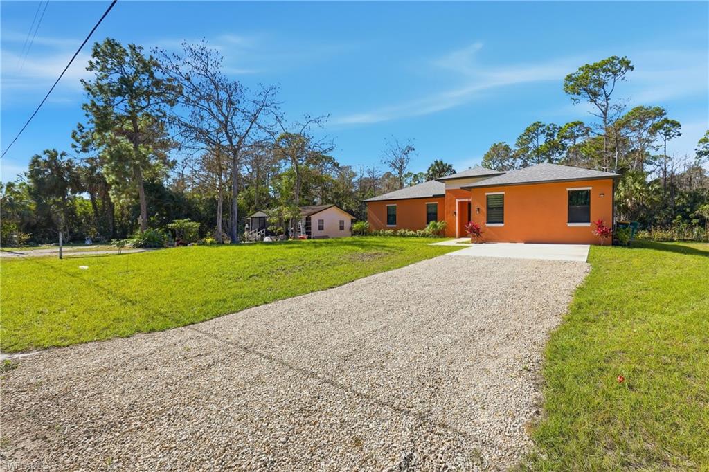 2167 Della Drive Naples, FL 34117 - Photo 5 of 38 Ranch-style home featuring gravel driveway, a front lawn, and stucco siding