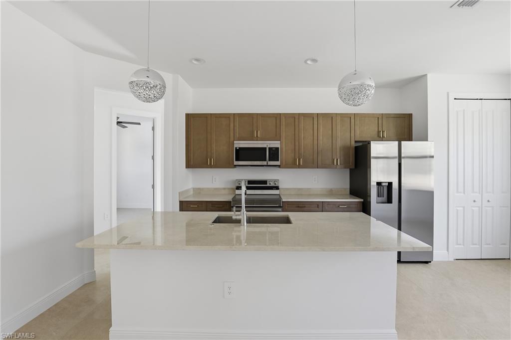 2167 Della Drive Naples, FL 34117 - Photo 10 of 38 Kitchen with appliances with stainless steel finishes, light stone counters, a kitchen island with sink, pendant lighting, and recessed lighting