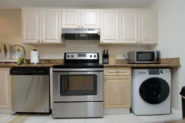 a kitchen with granite countertop white cabinets and stainless steel appliances