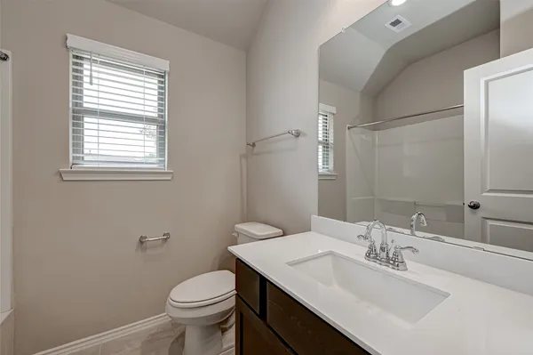 a bathroom with a toilet a sink a mirror and a window