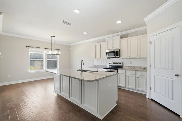 a kitchen with granite countertop white cabinets and stainless steel appliances