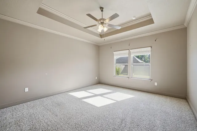 an empty room with windows and ceiling fan