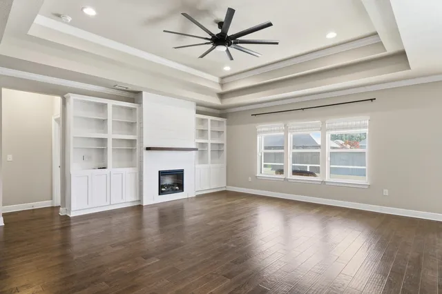 a view of a livingroom with a fireplace a ceiling fan and windows