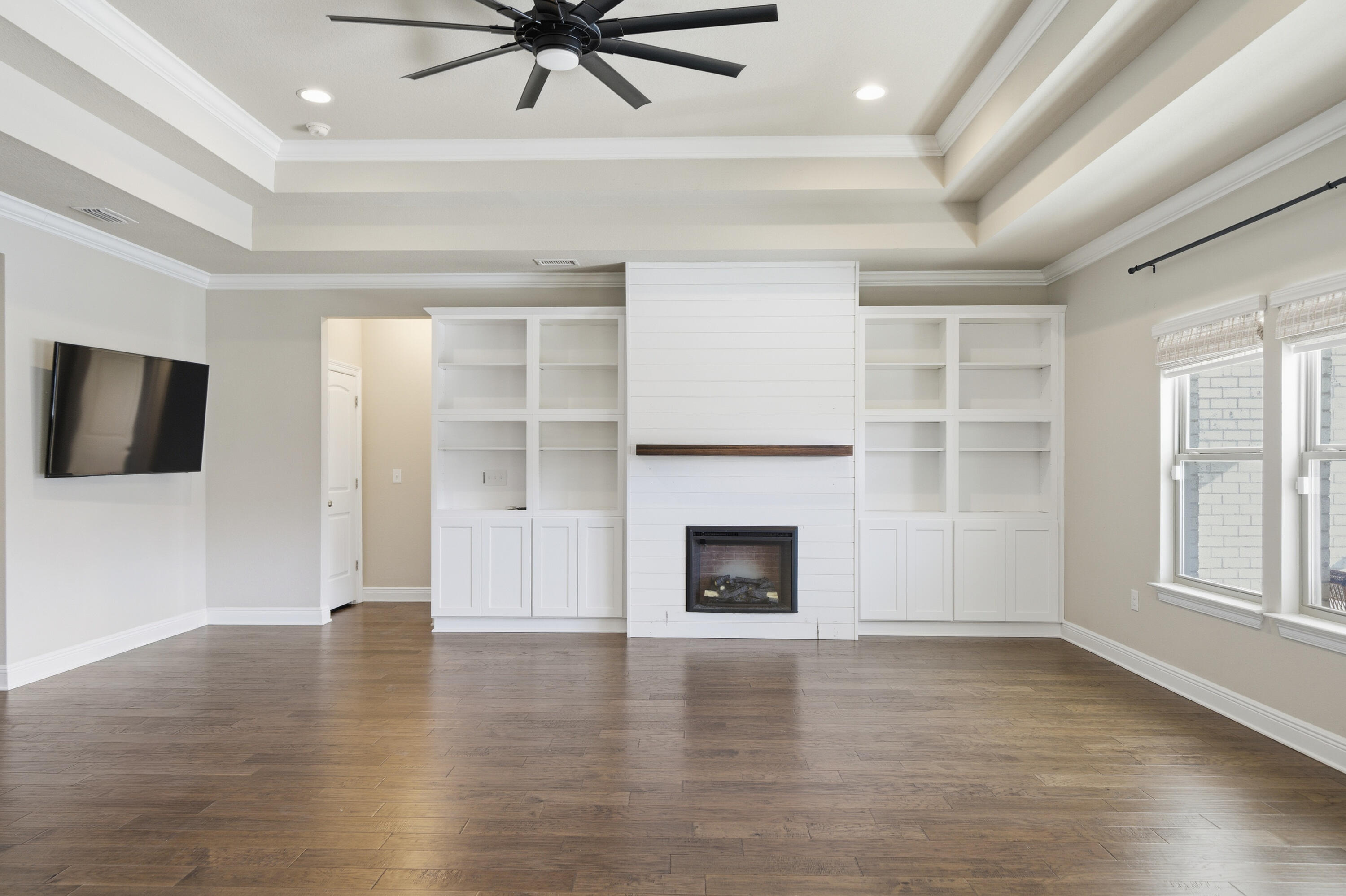 132 Wayne Trail Santa Rosa Beach, FL 32459 - Photo 8 of 43 an empty room with wooden floor a ceiling fan a fireplace and windows