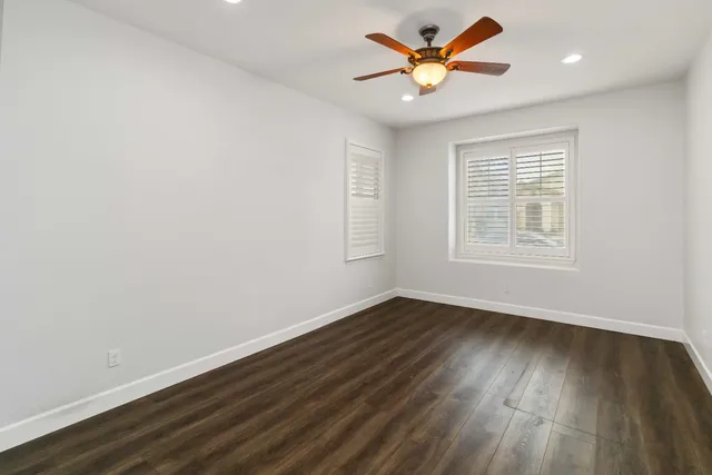 an empty room with wooden floor and windows