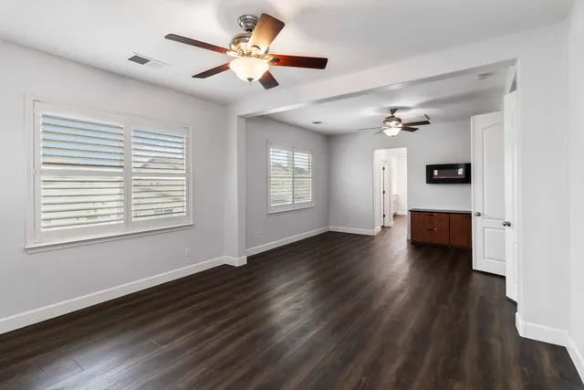 a view of empty room with wooden floor and fan