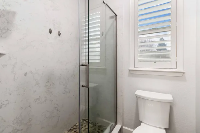 an empty room with wooden floor chandelier fan and windows