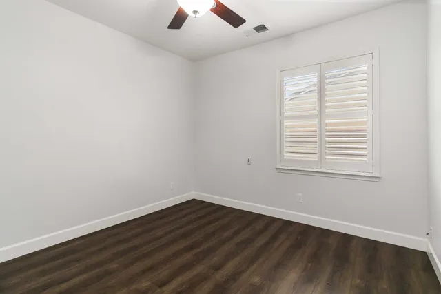 an empty room with wooden floor cabinet and ceiling fan