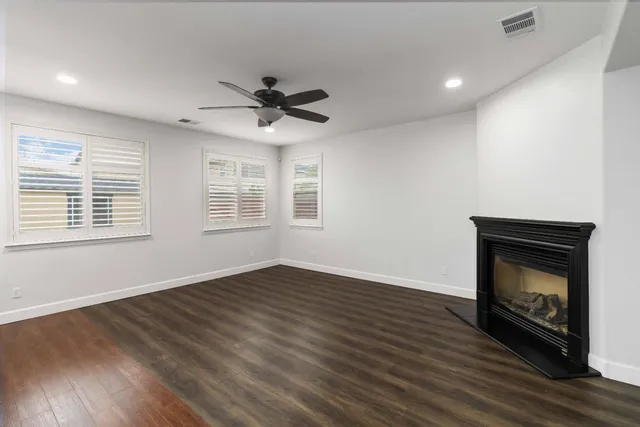a view of an empty room with kitchen and fireplace