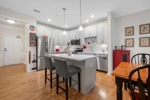 a kitchen with stainless steel appliances a dining table chairs refrigerator and microwave