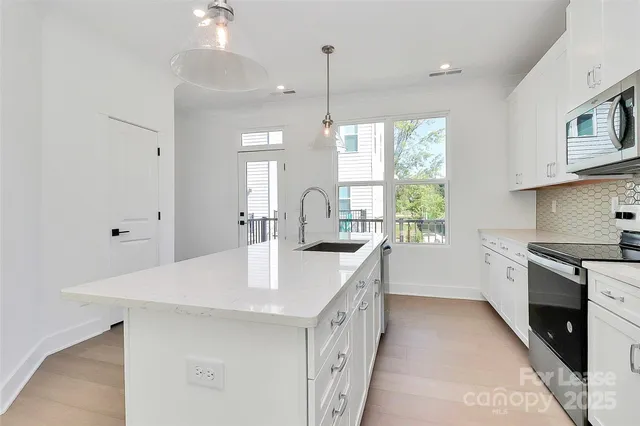 a large kitchen with cabinets appliances a sink and a window