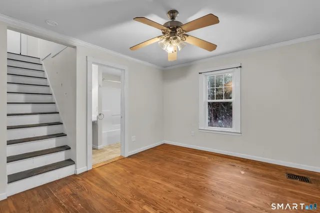 an empty room with wooden floor fan and windows