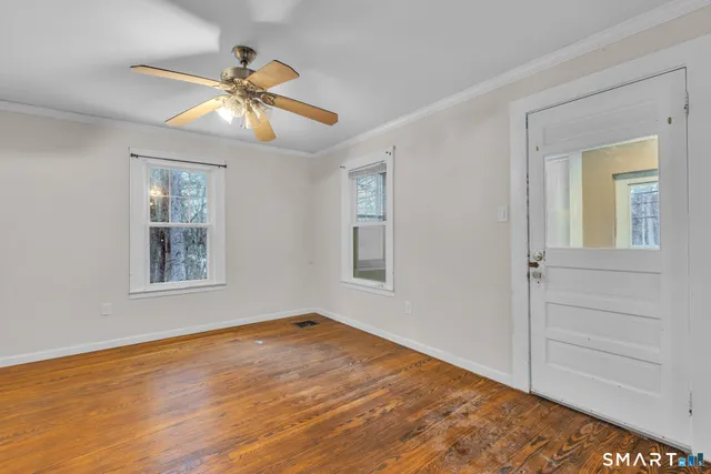 a view of an empty room with wooden floor and a chandelier fan