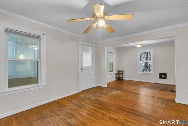 a view of a room with wooden floor and a ceiling fan