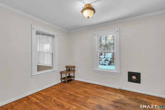 a view of an empty room with a window and wooden floor