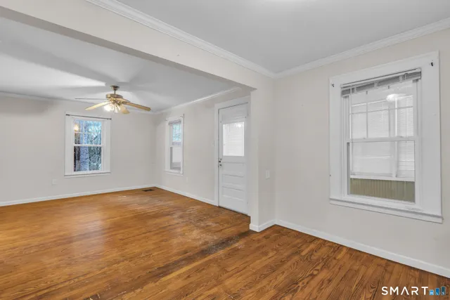 a view of empty room with wooden floor and fan