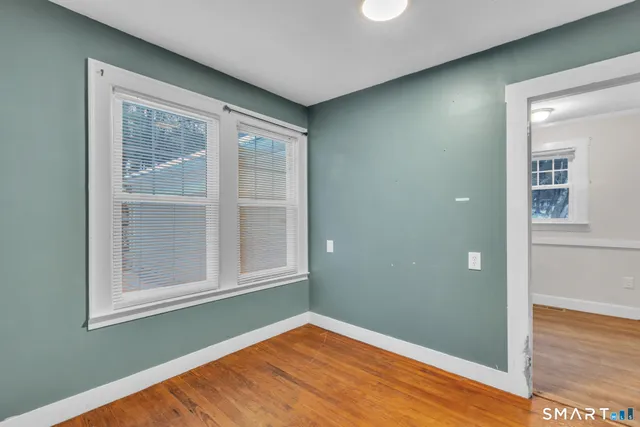 a view of an empty room with wooden floor and a window