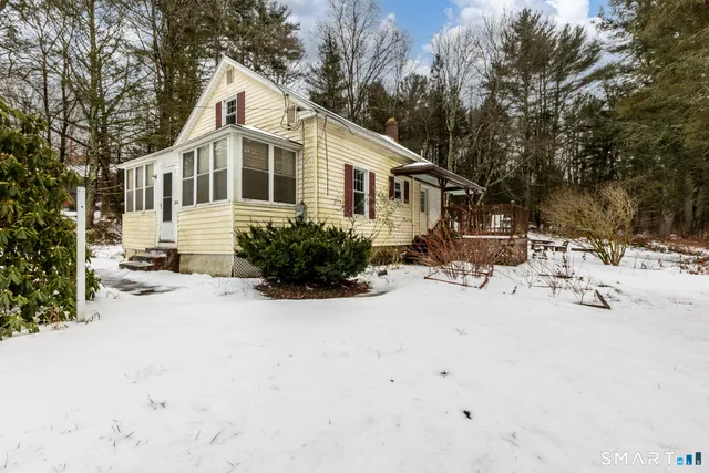 a view of a white house with a yard covered with snow in the road