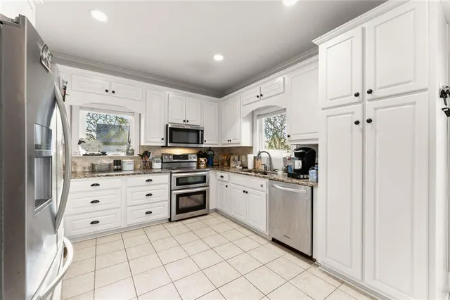 a kitchen with granite countertop white cabinets and stainless steel appliances