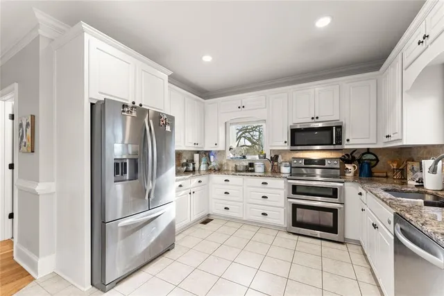 a kitchen with granite countertop white cabinets and stainless steel appliances