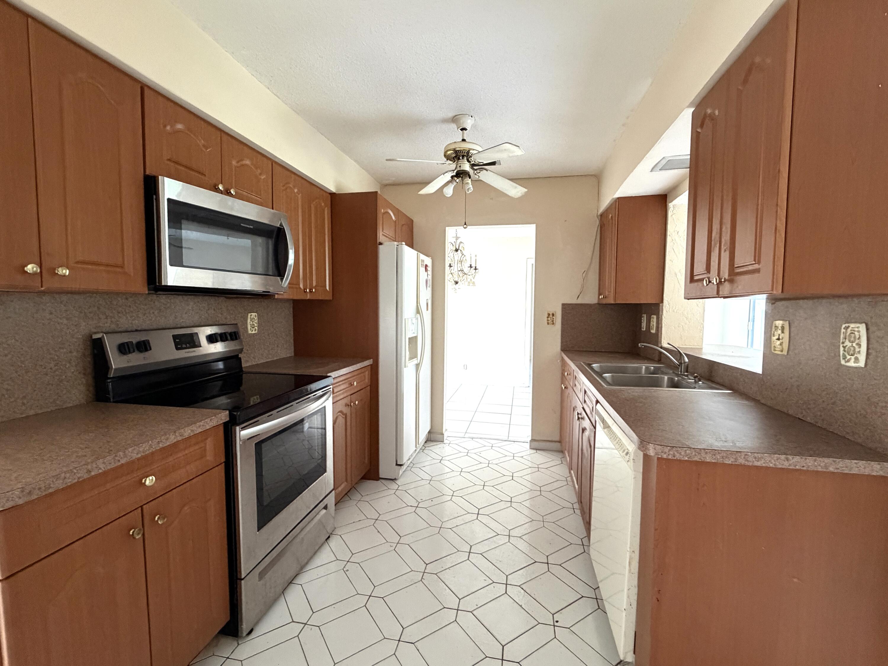 9210 Northwest 73rd Street Tamarac, FL 33321 - Photo 4 of 8 a kitchen with granite countertop a sink a stove top oven and cabinetry