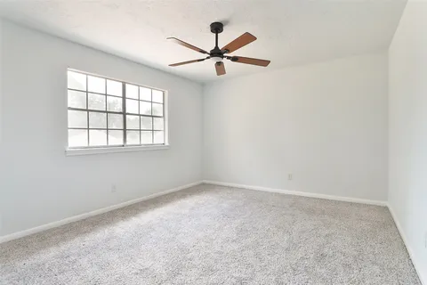 an empty room with windows and ceiling fan