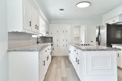 a large white kitchen with granite countertop a sink and dishwasher stove