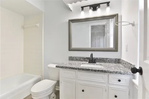 a bathroom with a toilet sink vanity tub and mirror