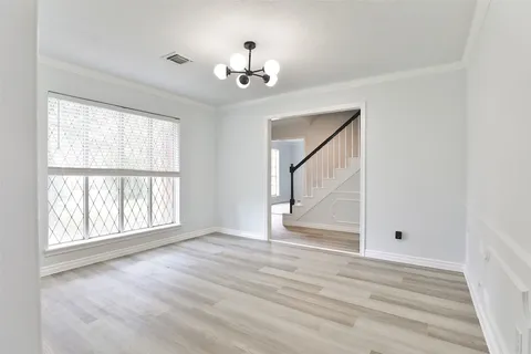 an empty room with wooden floor chandelier and windows