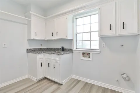 a kitchen with granite countertop white cabinets and a window