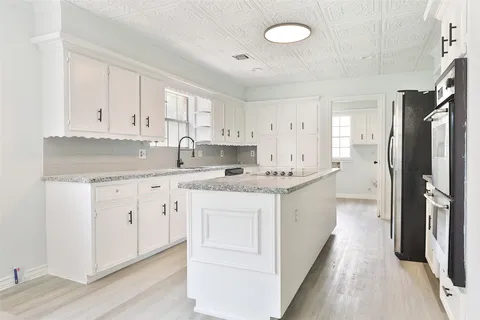 a kitchen with kitchen island granite countertop a sink cabinets stainless steel appliances and a counter space