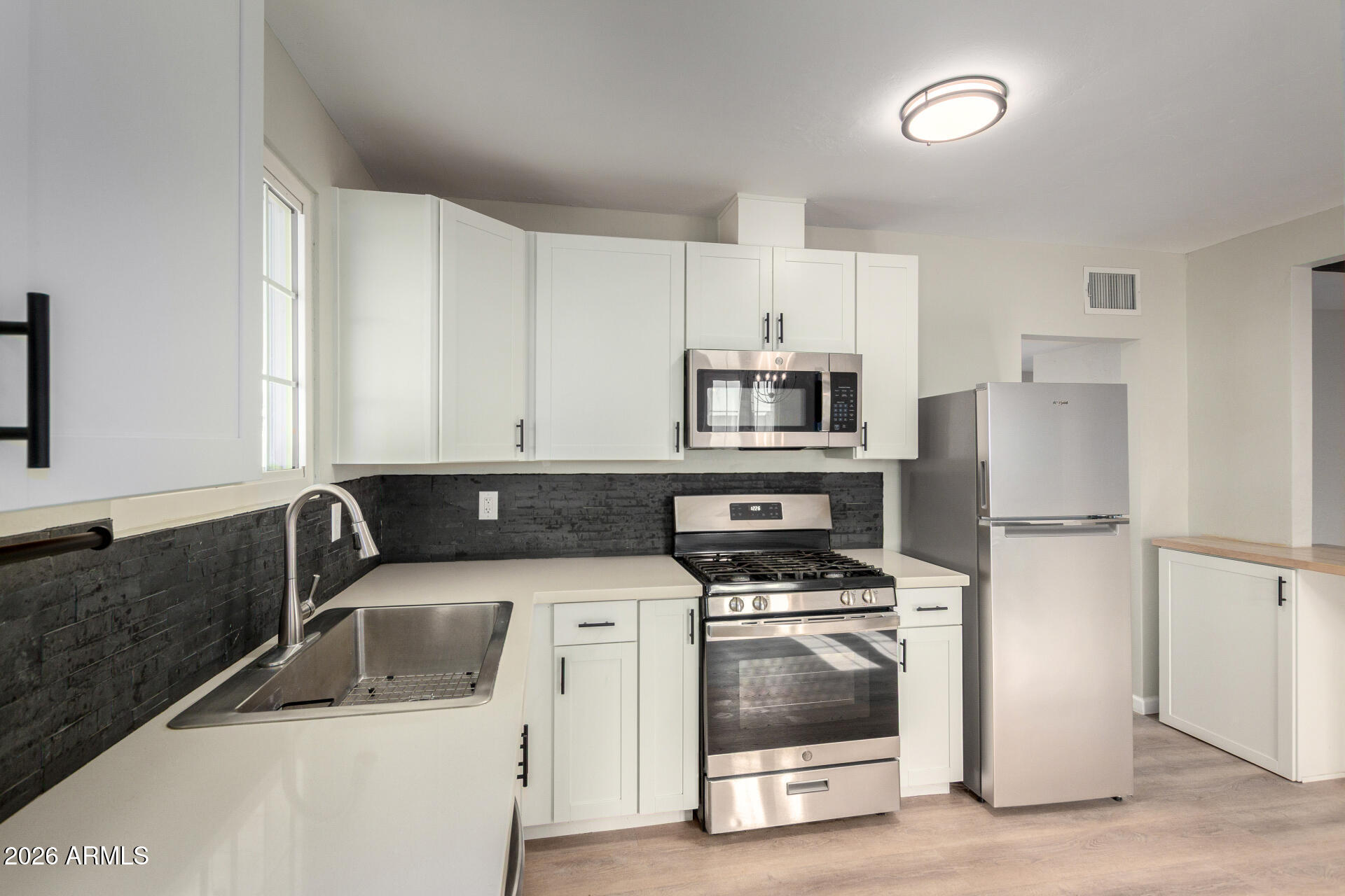 4010 North 11th Avenue Phoenix, AZ 85013 - Photo 11 of 22 a kitchen with white cabinets sink and stainless steel appliances