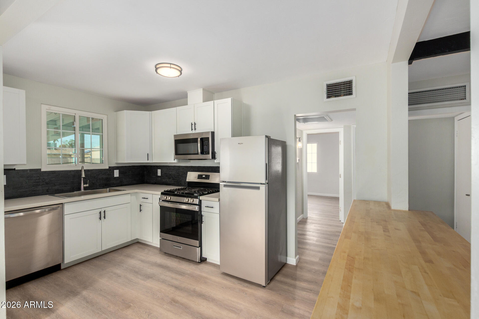 4010 North 11th Avenue Phoenix, AZ 85013 - Photo 10 of 22 a kitchen with white cabinets and stainless steel appliances