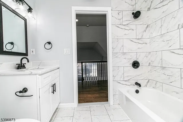 a bathroom with a tub a sink and mirror