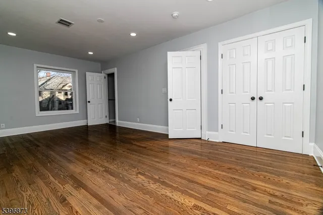 a view of an empty room with wooden floor and window